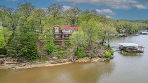 A lakeside property with a large house, dock, and surrounding greenery.