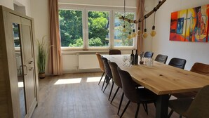Een eethoek met een houten tafel, stoelen en uitzicht op groen.