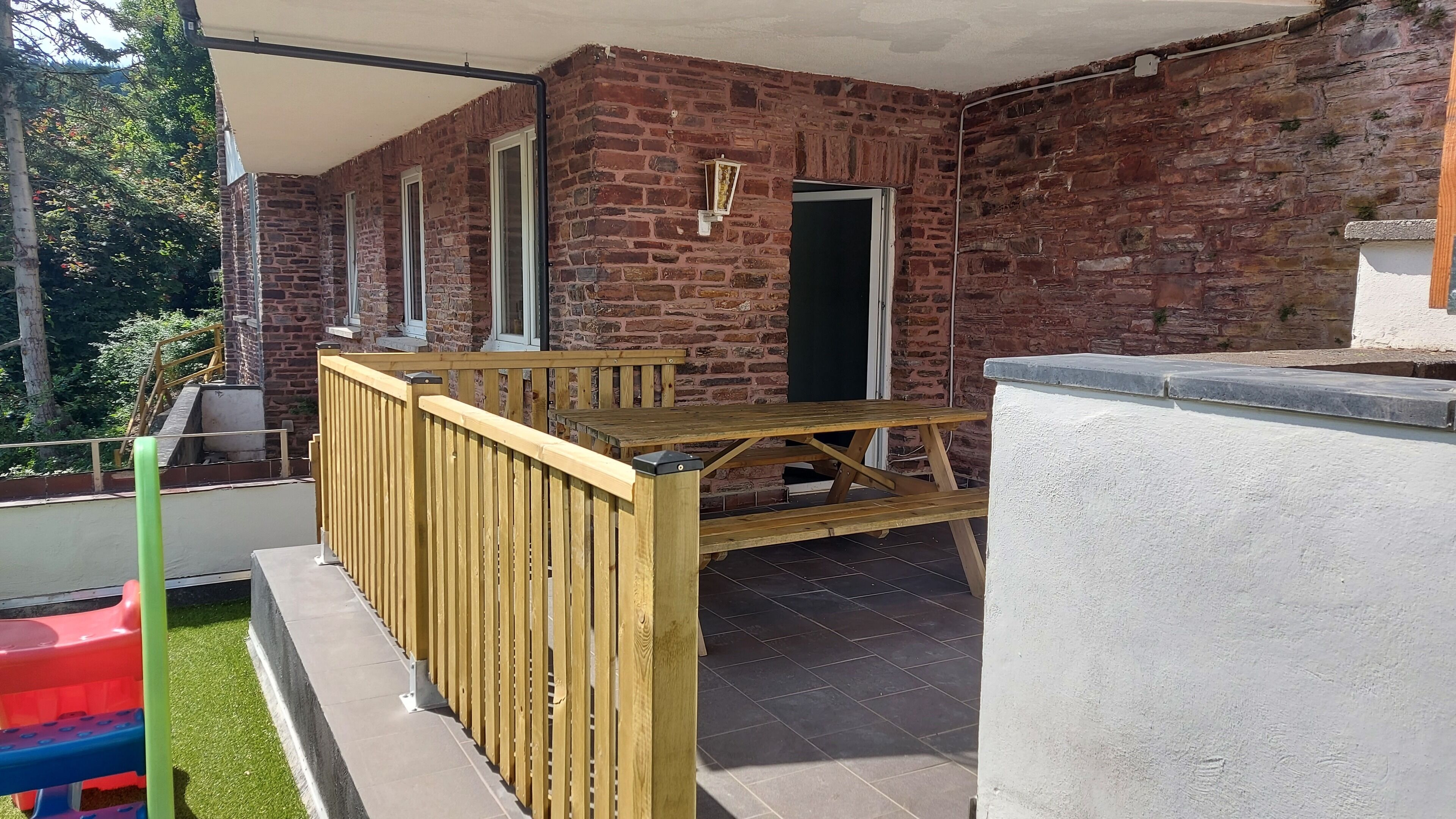A brick building with a wooden deck and a white wall.
