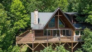 Une cabane en bois dotée d’un balcon, entourée d’une forêt dense.