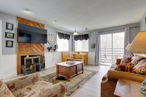 Una sala de estar con chimenea, sofá, mesa de centro, televisor y un comedor con mesa y sillas.