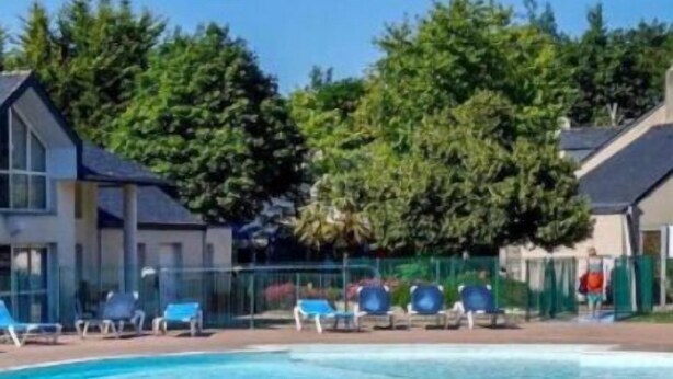 Une piscine à l’eau d’un bleu cristallin, entourée de chaises longues et bordée d’un chemin en briques.
