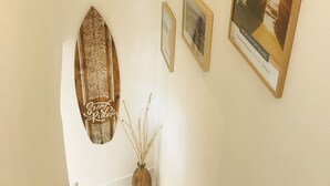Un escalier orné d’un tableau encadré représentant un coucher de soleil sur une formation rocheuse, un objet décoratif en bois et un petit vase contenant des branches.