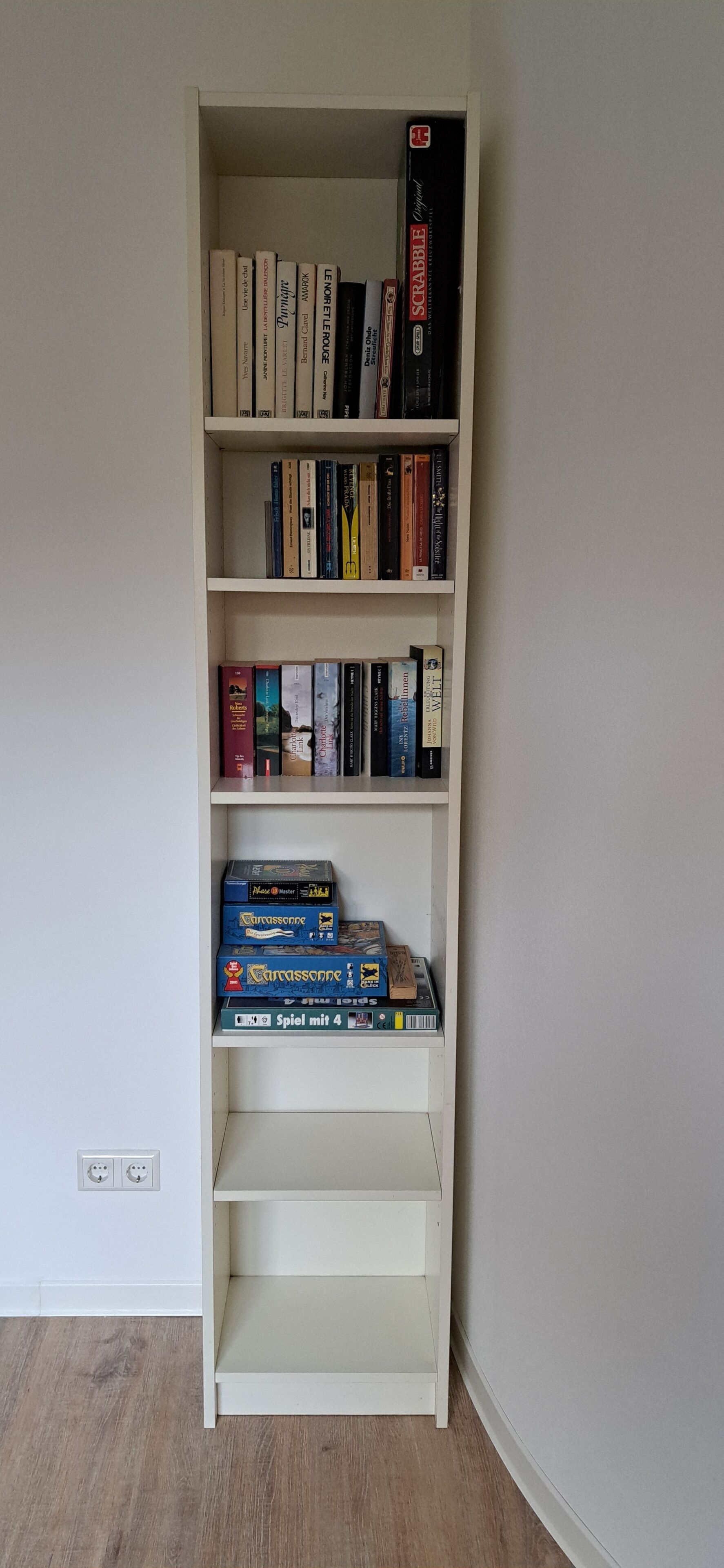 En hvid reol med bøger og brætspil.