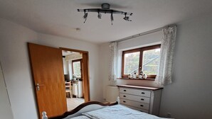 A bedroom with a bed, a dresser, a window with curtains, and a ceiling fan.