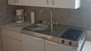 A kitchen with white cabinets, a stainless steel sink, a coffee maker, and a stove.
