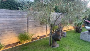 A garden with a wooden fence, a small tree, a sculpture, and a planter. - ANGLET, 8 pers COAST HOUSE WITH SWIMMING POOL, NEAR THE BEACH, cycle path, GOLF (Anglet)