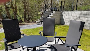 Une terrasse extérieure avec une table ronde et trois chaises.
