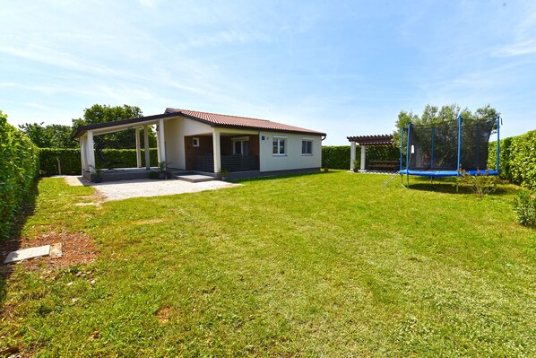 A house with a covered porch, a fenced backyard, and a trampoline.