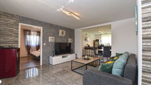 A modern living room with a flat-screen TV, a grey sofa, and a coffee table.
