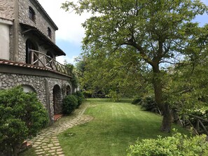 Un bâtiment en pierre avec un chemin pavé menant à une pelouse bien entretenue.