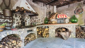 A rustic kitchen with a stone hearth, wooden beams, and various cooking utensils. - Rocca Angelica - Villa with swimming pool, 40 min far from Positano (Santa Maria del Castello)