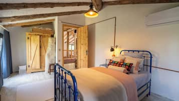 Un dormitorio con techo de madera, una cama con estructura metálica azul y un ventanal grande.