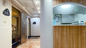 A hotel lobby with a marble floor, a reception desk, and a staircase leading to another floor.