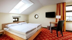 Ein Hotelzimmer mit Bett, Schreibtisch, Stuhl, Fernseher und einem Oberlicht.