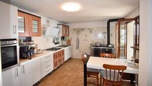 A compact kitchen with white cabinets, a stove, and a dining area with a table and chairs.