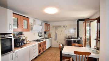 Una cucina compatta con mobili bianchi, un fornello e un'area pranzo con tavolo e sedie.