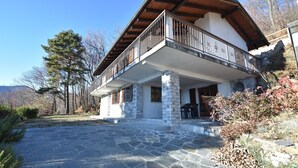 A stone building with a balcony, stone pillars, and a stone patio.