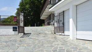 A stone-paved entrance to a building with a gated driveway, a mailbox, and outdoor seating.