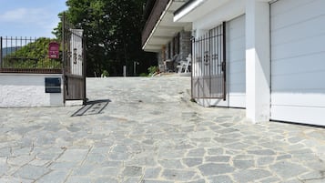 Ingresso in pietra a un edificio con vialetto recintato, cassetta delle lettere e area salotto esterna.