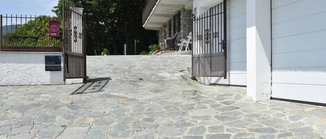 A stone-paved entrance to a building with a gated driveway, a mailbox, and outdoor seating.
