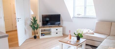 Una sala moderna con televisor, sofá y mesa de centro.
