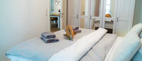 A bedroom with a bed, a wardrobe, and a bathroom visible through an open door.