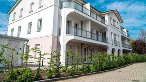 A multi-story residential building with balconies, a pink facade, and a clear blue sky. - Erdgeschosswohnung Dünen-residenz 11 im Ostseebad Wustrow (Ostseebad Wustrow)