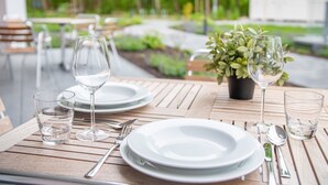 An outdoor dining area with wooden tables, white plates, and clear glasses. - Erdgeschosswohnung Dünen-residenz 11 im Ostseebad Wustrow (Ostseebad Wustrow)