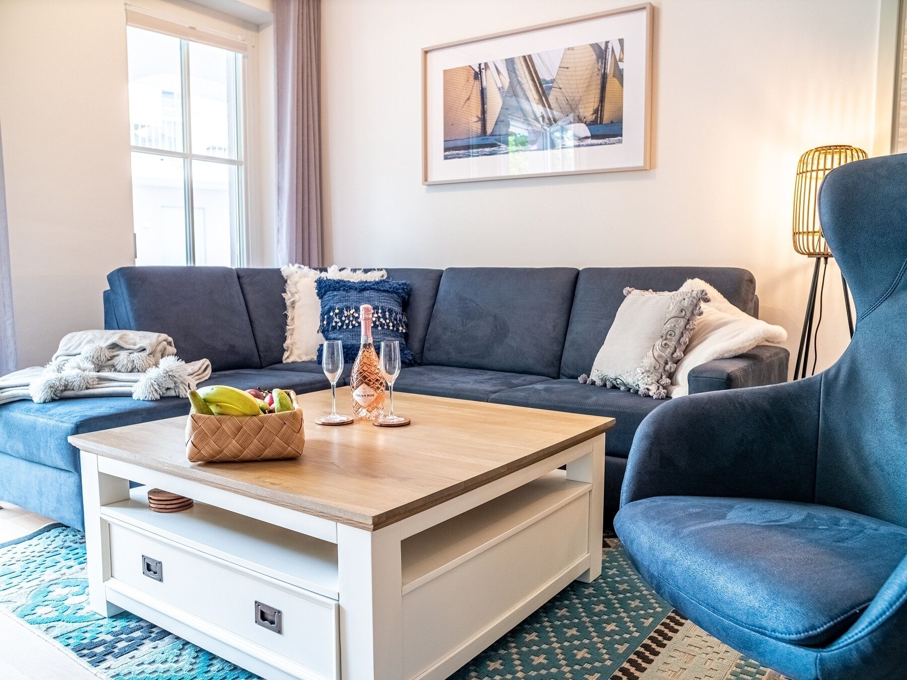 Een moderne woonkamer met een donkerblauwe bank, een houten salontafel en een ingelijste foto aan de muur.
