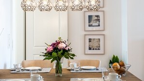 A dining area with a wooden table set for four, a vase of flowers, and a framed picture of a ship on the wall. - Erdgeschosswohnung Dünen-residenz 11 im Ostseebad Wustrow (Ostseebad Wustrow)