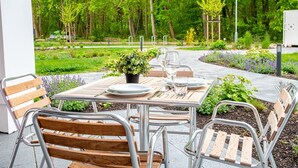 Eine Terrassengruppe im Freien mit einem Esstisch, umgeben von Metallstühlen und einem Blumentopf.