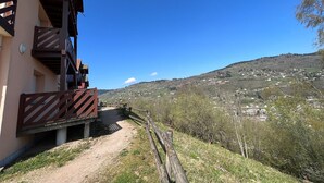 Ein Gebäude mit einem Holzbalkon und einem Feldweg, der zu einer hügeligen Landschaft führt.