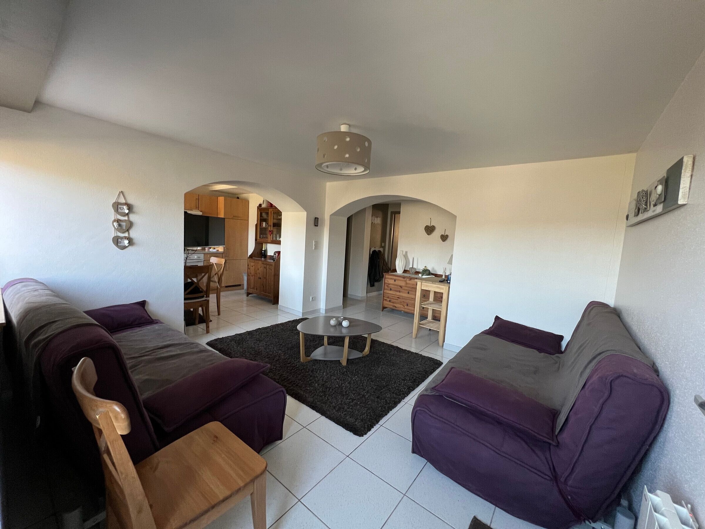Een woonkamer met een bank, een salontafel en een eethoek met een tafel en stoelen.