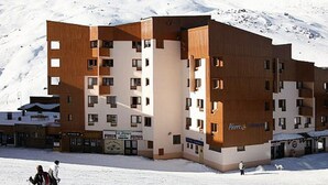 A multi-story hotel with a modern design, featuring a mix of wood and white exterior panels. - Spacious 3-room cabin, 6 pers, ski-in/ski-out, free parking (Les Belleville)