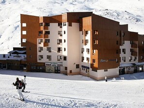 A multi-story hotel with a modern design, featuring a mix of wood and white exterior panels. - Spacious 3-room cabin, 6 pers, ski-in/ski-out, free parking (Les Belleville)