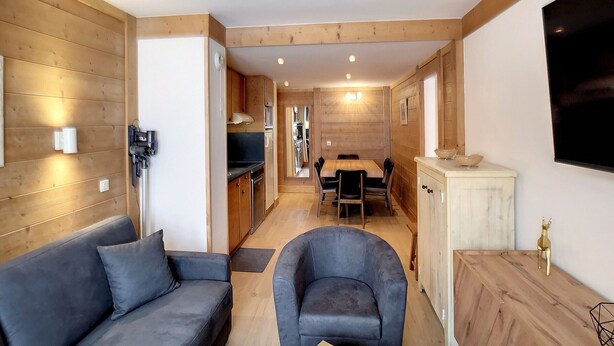 A compact living space with a sofa, armchair, wooden walls, a dining area, and a kitchen. - Spacious 3-room cabin, 6 pers, ski-in/ski-out, free parking (Les Belleville)