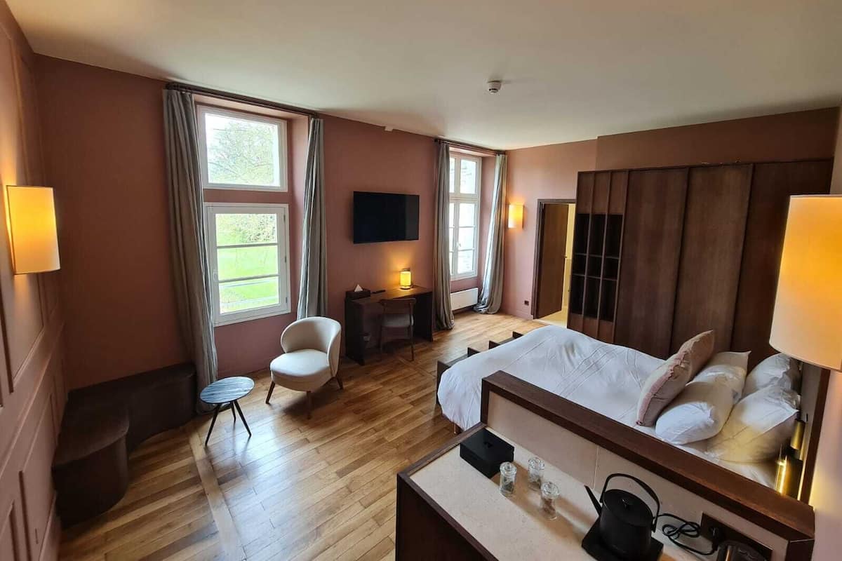A hotel room with a bed, a desk, a chair, a TV, and a window.