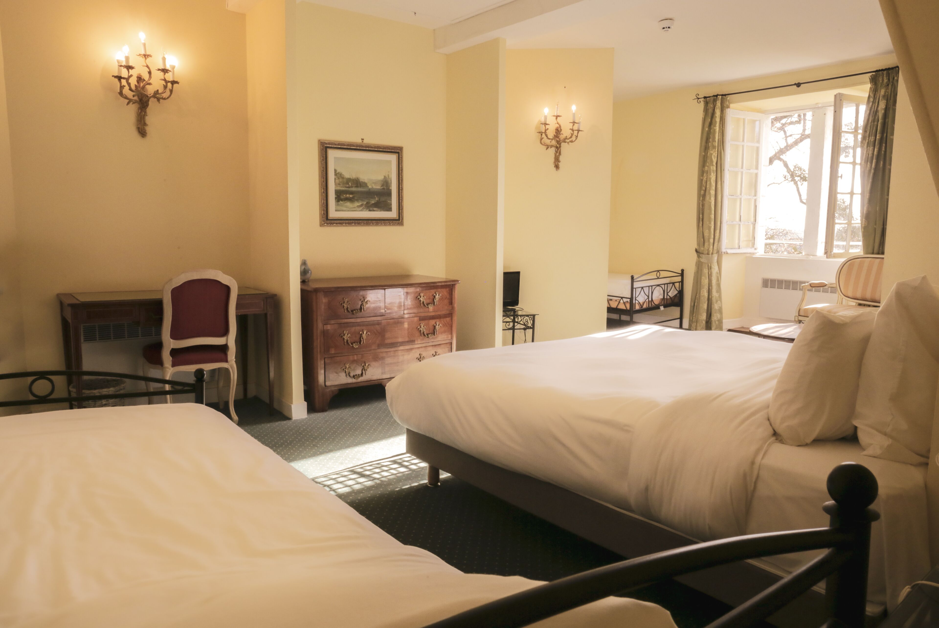 A hotel room with two beds, a desk, a chair, a dresser, and a window with curtains.