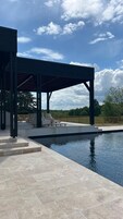 Un espace extérieur abrité doté d’une piscine, d’un escalier menant à une terrasse et offrant une vue sur le paysage environnant.