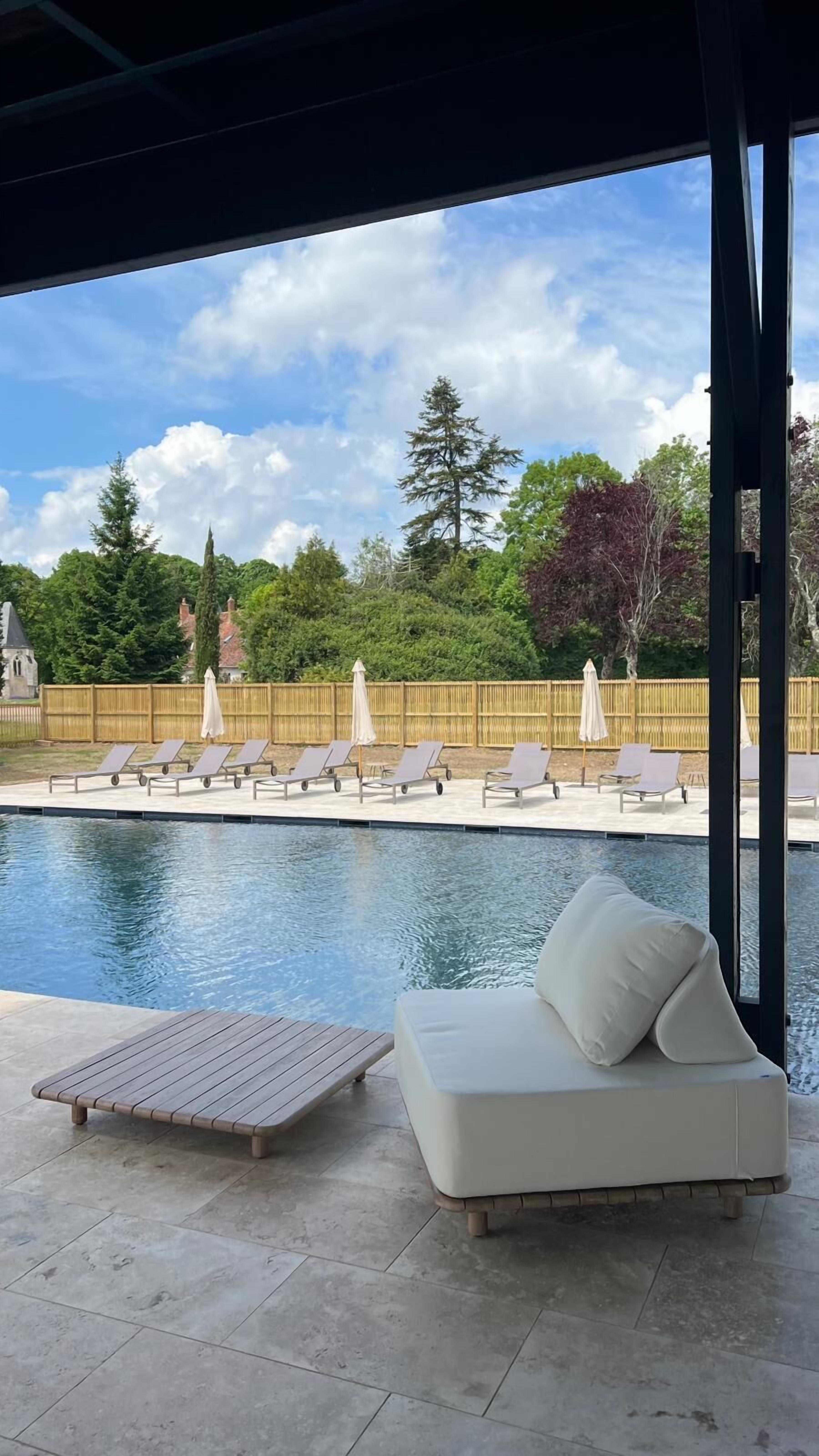 A pool area with lounge chairs and a white sofa.