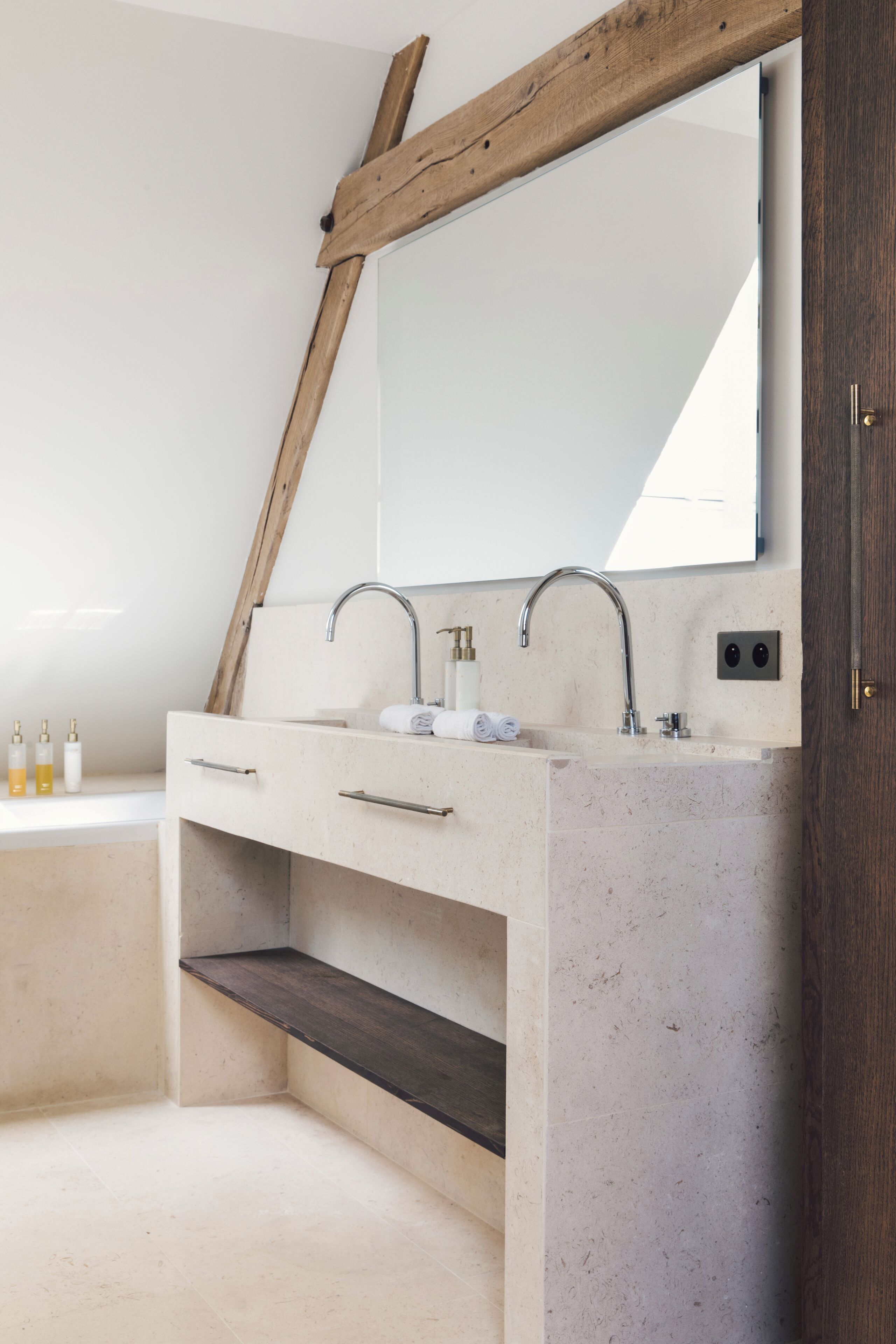 Un baño con un espejo grande, dos lavamanos y una viga de madera sobre el espejo.
