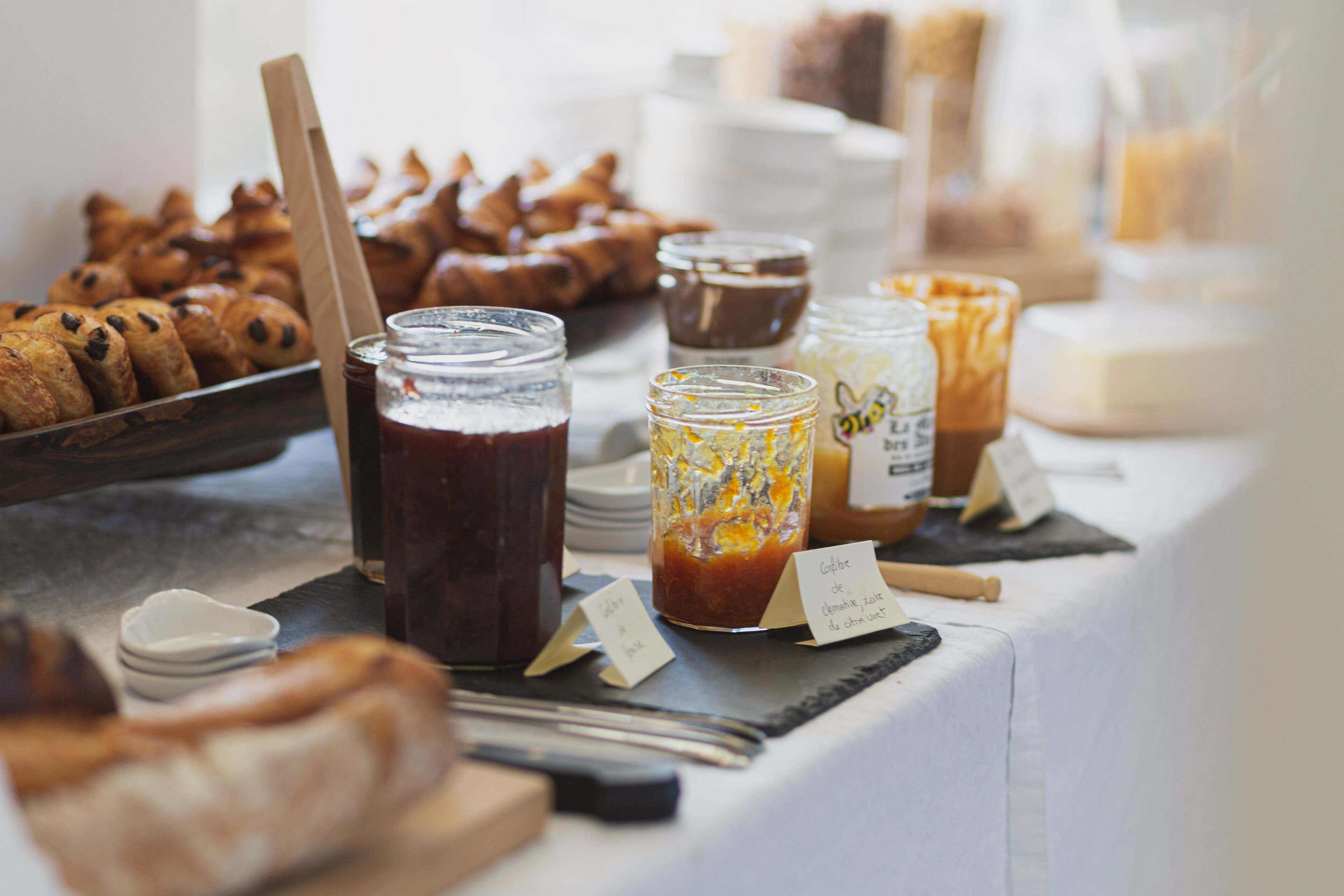 A breakfast buffet with various pastries, jams, and spreads.