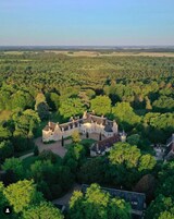 Un vaste domaine historique, entouré d’une forêt dense.
