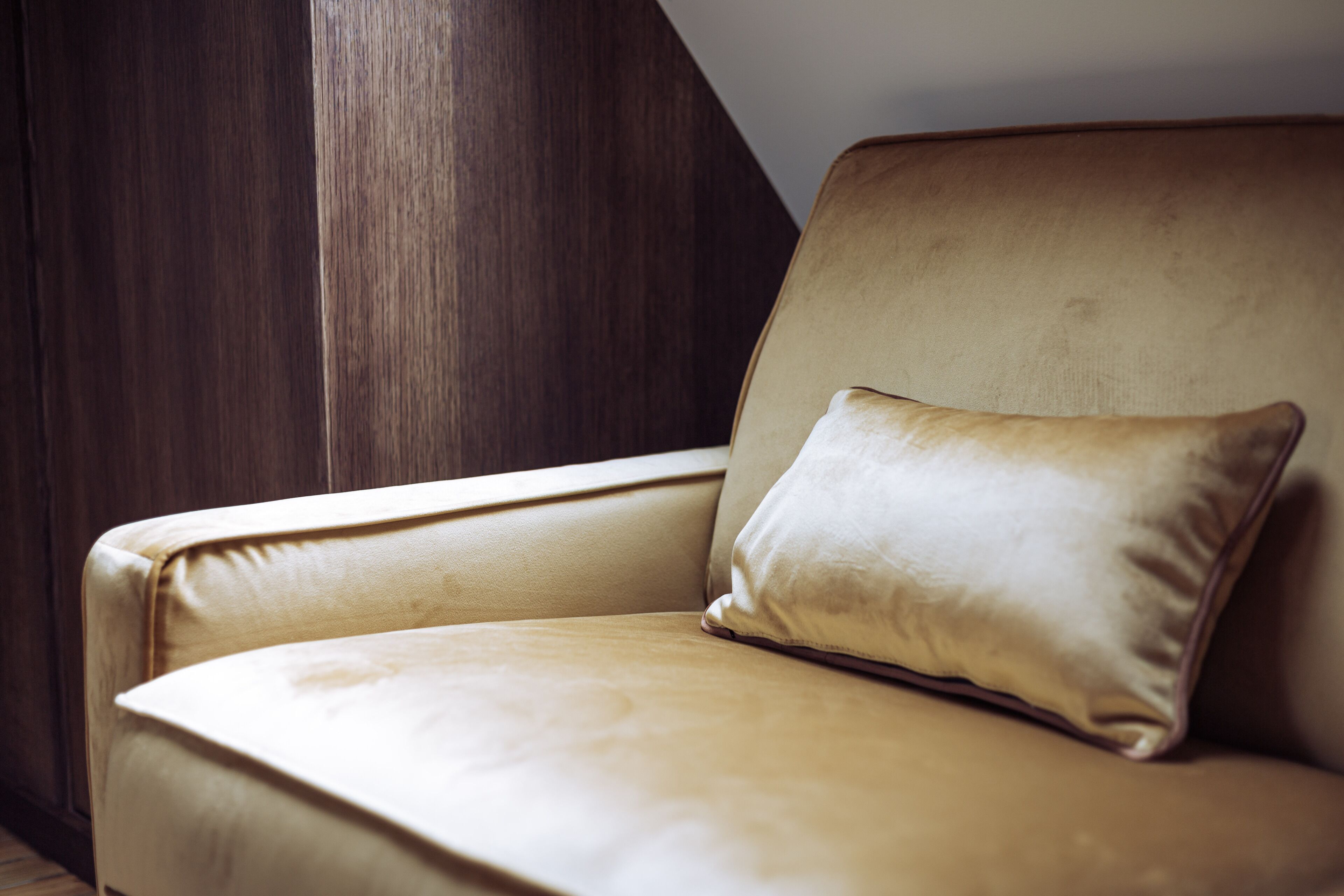 Un fauteuil en cuir marron, agrémenté d’un coussin assorti, est placé contre un mur en bois.