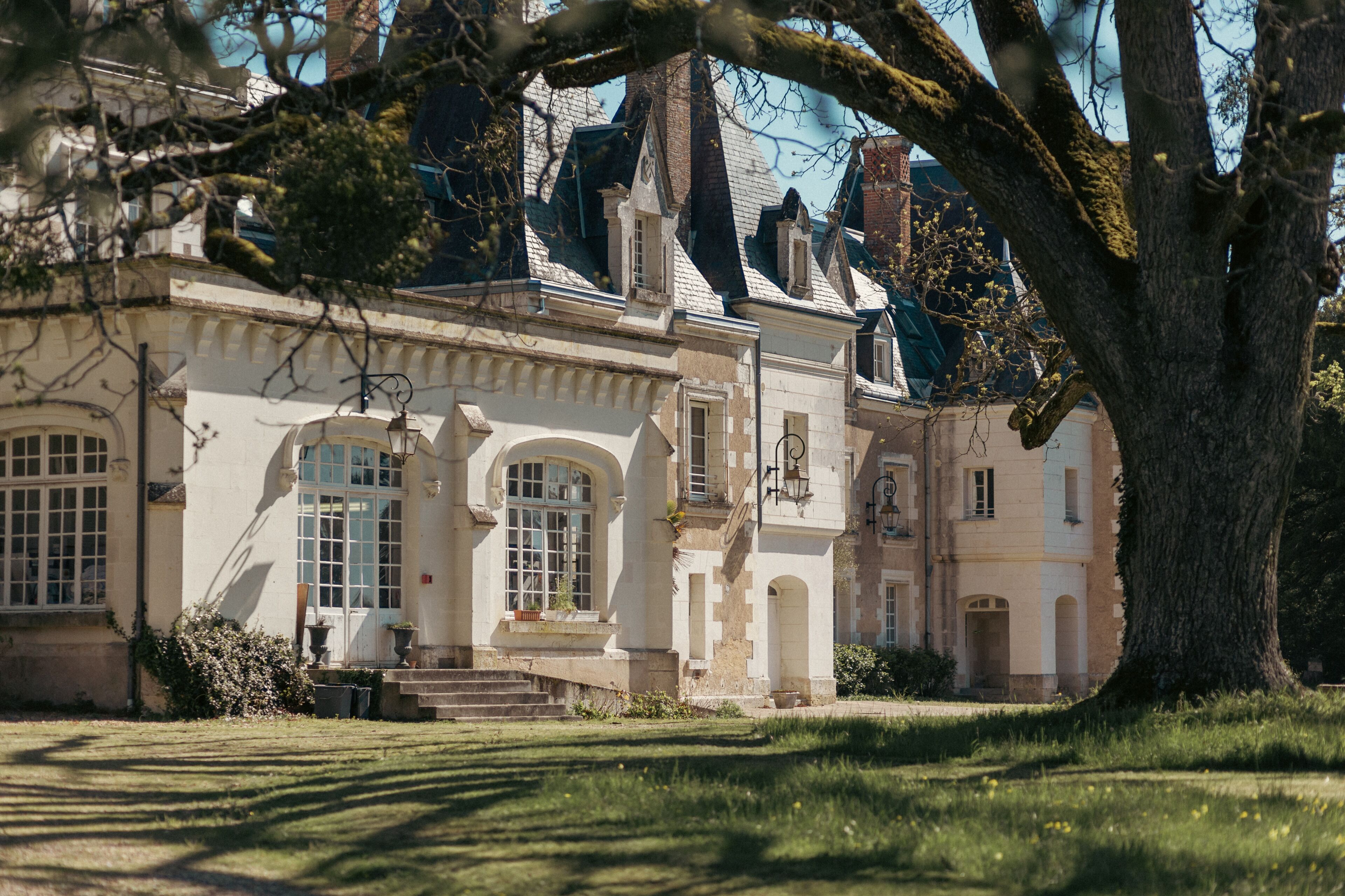 Un bâtiment historique à la façade symétrique, doté de grandes fenêtres et d’une entrée centrale avec des marches.