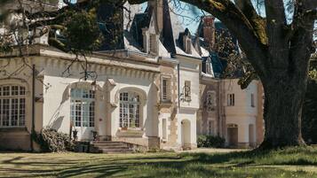Un bâtiment historique à la façade symétrique, doté de grandes fenêtres et d’une entrée centrale avec des marches.