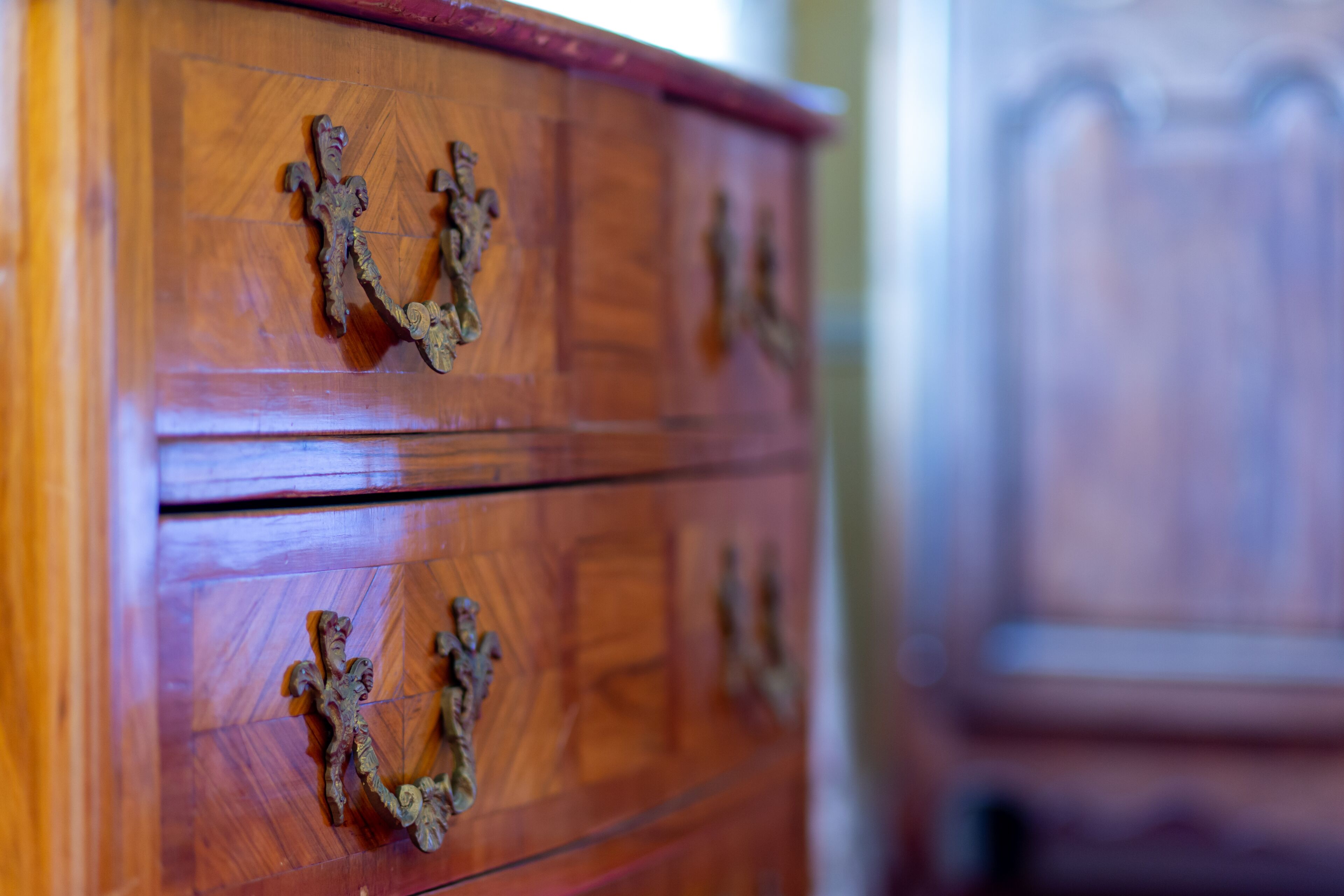 A wooden dresser with ornate metal handles.