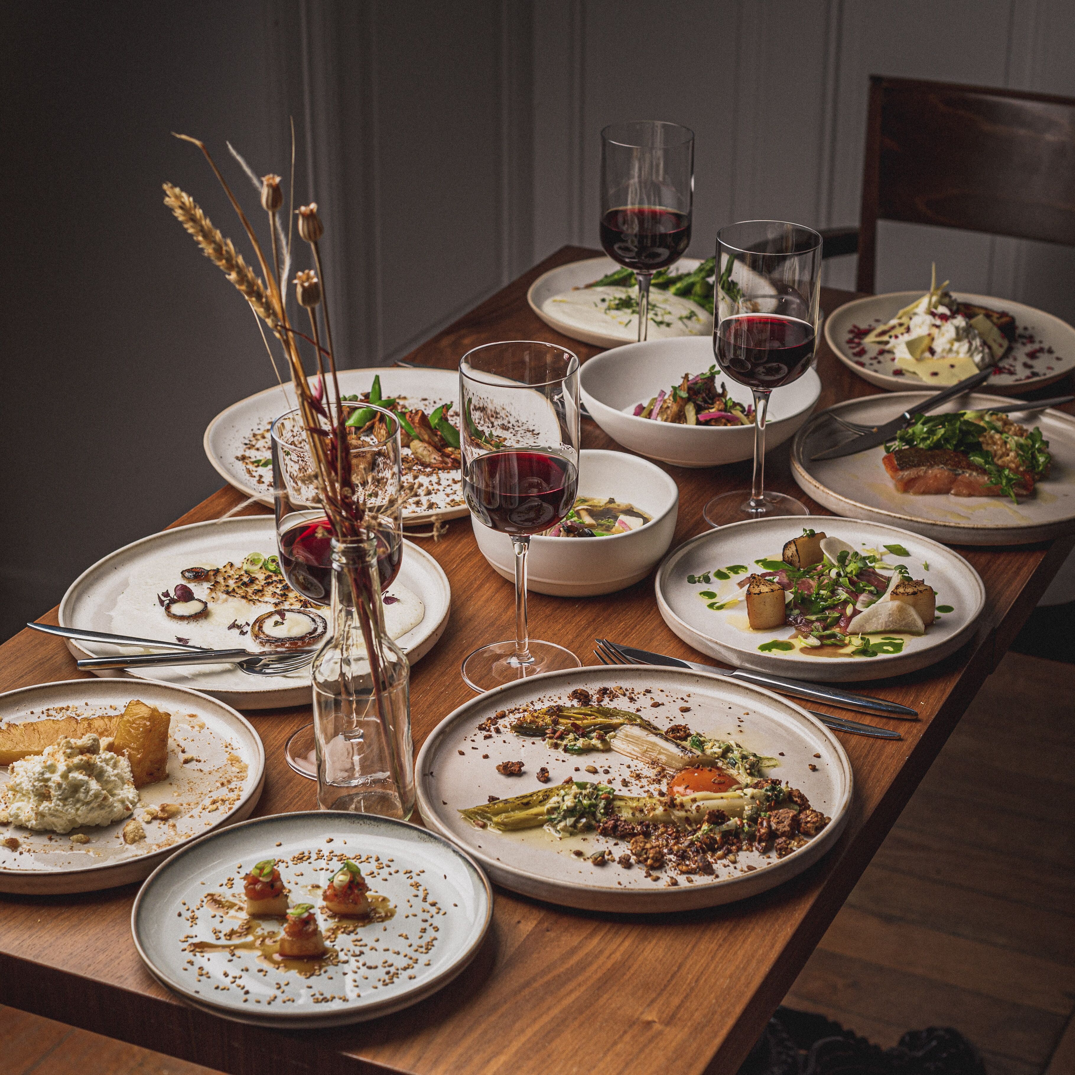A dining table with various dishes, wine glasses, and cutlery.