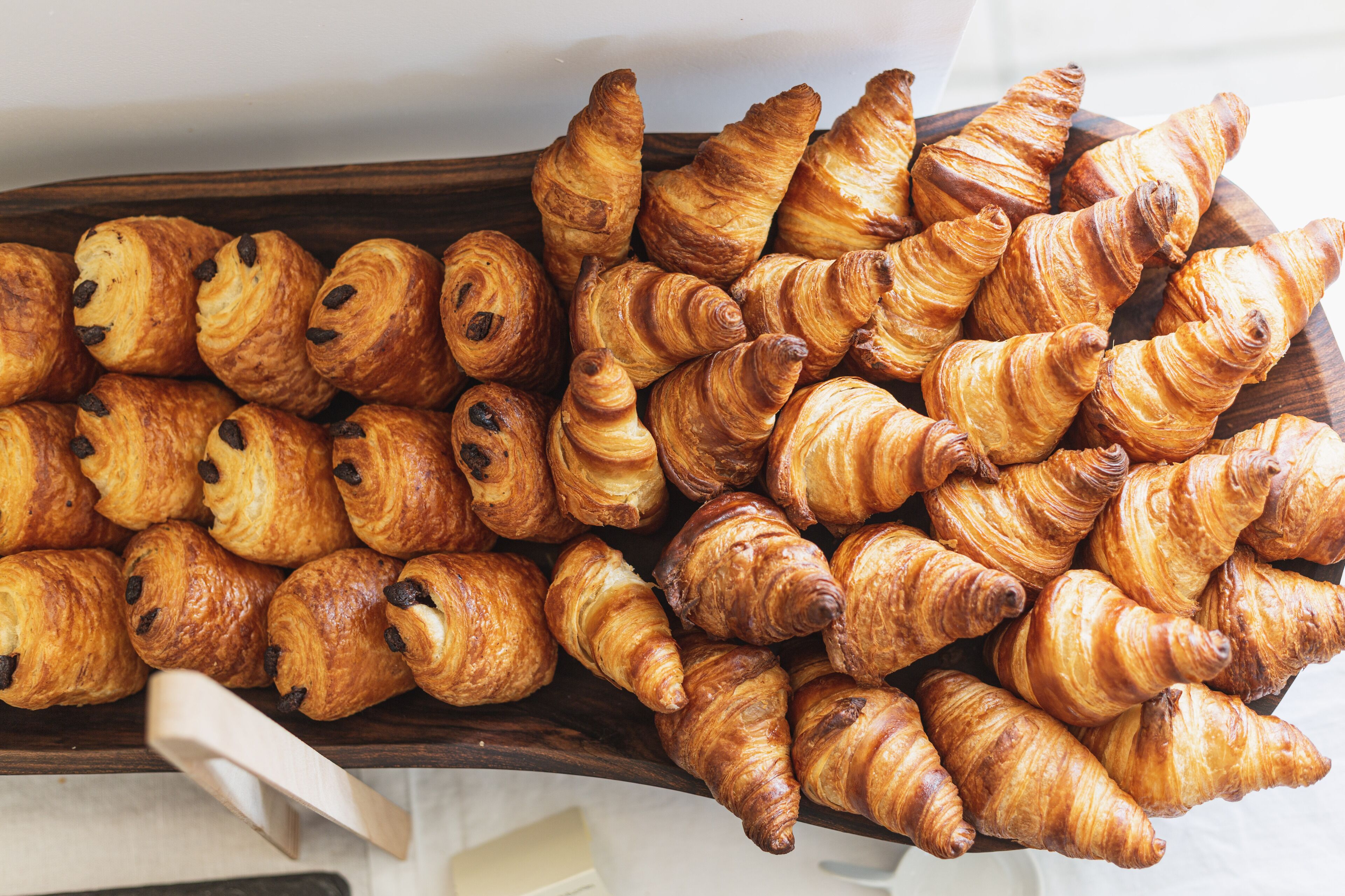 A wooden tray filled with assorted croissants.